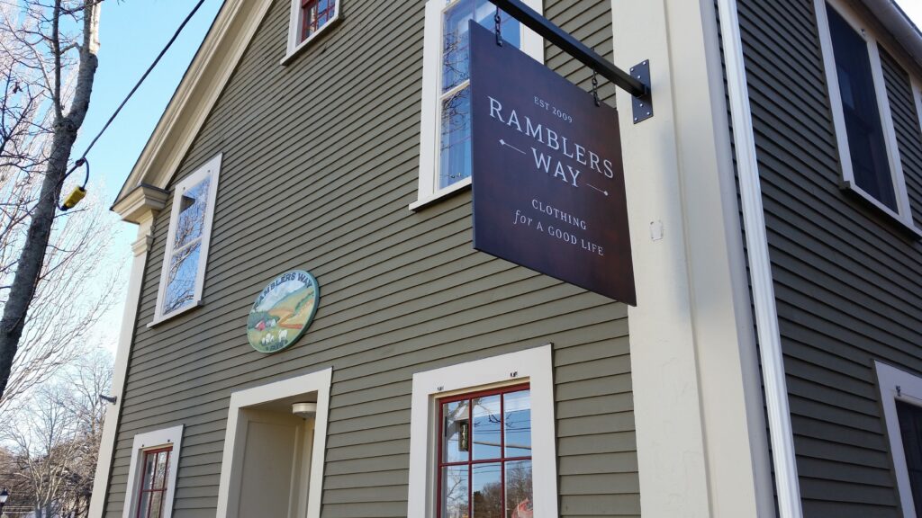 Ramblers Way clothing store hanging metal sign on exterior