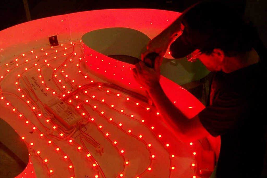 Technician installing inner lighting for a face-lit sign letter